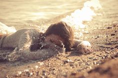 a woman laying on the beach in the water