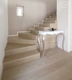 a white table sitting on top of a wooden floor next to a set of stairs