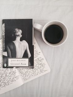 a cup of coffee sitting on top of an open book