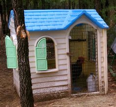 a small dog house with a blue roof and window on the outside, next to a tree