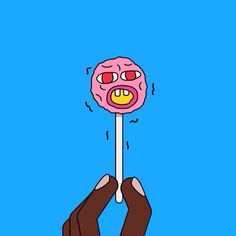 a hand holding a pink donut on a toothpick in front of a blue background