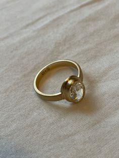 a gold ring sitting on top of a white sheet with a diamond in the middle