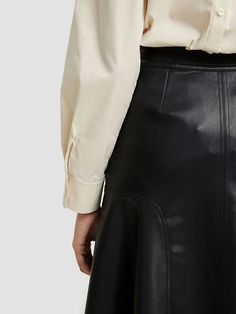 a woman wearing a white shirt and black leather skirt