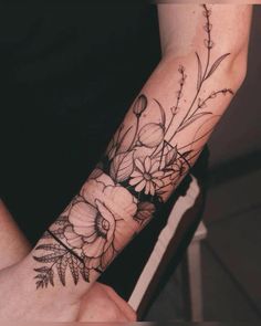 a woman's arm with flowers and leaves tattooed on the wrist, in black and white