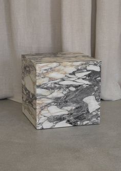 a marble block sitting on top of a floor next to a white curtained window