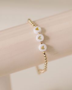 handcrafted stretch bracelet made with white + gold heart beads and 14k gold filled 3mm beads customize with 3-6 letters - name, monogram, city, anything you choose! made by artists in the USA Length - 6.5 inches White Heart Charm Bracelet For Everyday, Dainty White Stretch Bracelet As Gift, Personalized White Heart Bracelet For Everyday Wear, Dainty White Personalized Heart Bracelet, Dainty Personalized White Heart Bracelet, Personalized White Heart Bracelet For Everyday, White Heart-shaped Jewelry With Letter Beads, Personalized White Jewelry With Heart Charm, Dainty White Name Bracelet For Everyday