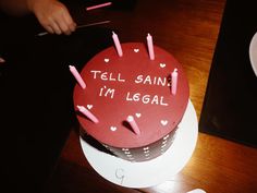 a cake that has been decorated with candles and writing on the top it says tell saint i'm legal