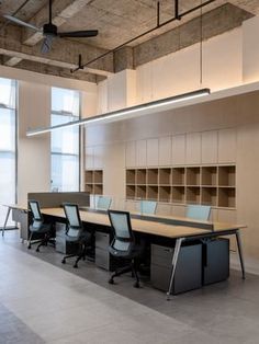 an empty conference room with desks and chairs in it, along with shelves on the wall