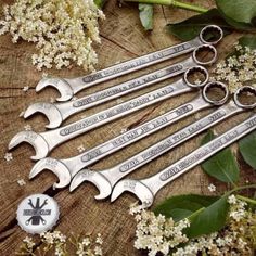 six wrenches sitting next to each other on top of a wooden table with flowers