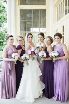 a group of women standing next to each other in front of a building holding bouquets