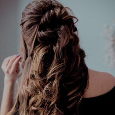 a woman is brushing her hair in front of a mirror while wearing a black top