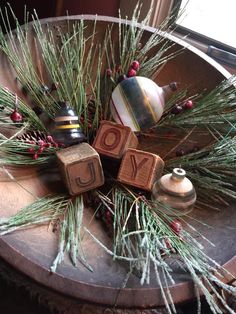 the word joy spelled with wooden blocks surrounded by pine branches and other holiday decor items