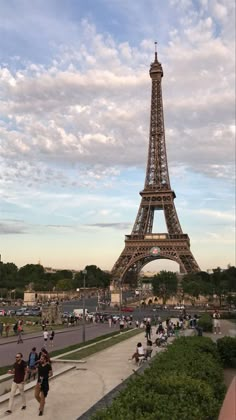 the eiffel tower is surrounded by people walking and sitting in front of it