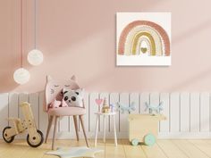 a child's room with pastel pink walls and wooden flooring, a rocking chair, toy animals, and a rainbow wall hanging on the wall