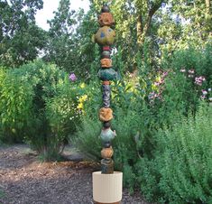 there is a tall sculpture made out of balls and yarn in the middle of a garden