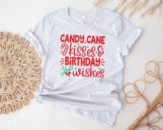 a t - shirt that says candy cane kisses and birthday wishes on it next to some straws