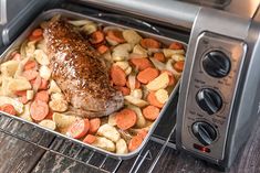 a roasting pan filled with meat, potatoes and carrots next to an open toaster oven