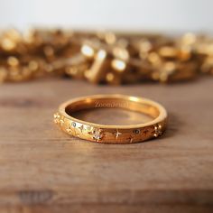 a gold ring with stars on it sitting on a wooden table next to some confetti