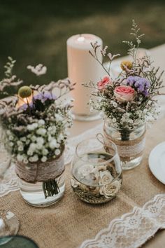 three vases filled with flowers sitting on top of a table next to a candle