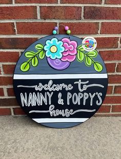 a sign that says welcome to nanny & poppy's house on the side of a brick wall