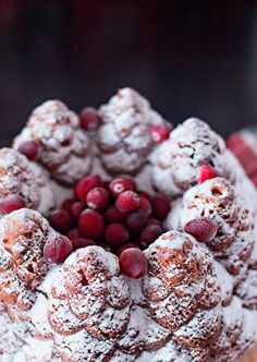 a bundt cake with cranberries and powdered sugar on top is shown