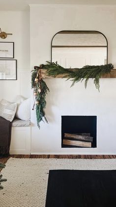 a living room filled with furniture and a fire place covered in greenery next to a mirror