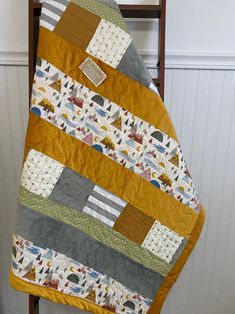 a quilted blanket is hanging on a wooden chair in front of a white wall