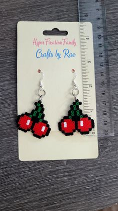 a pair of red and black earrings sitting on top of a ruler