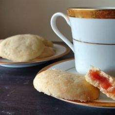 two plates with pastries on them next to a cup and saucer filled with jam