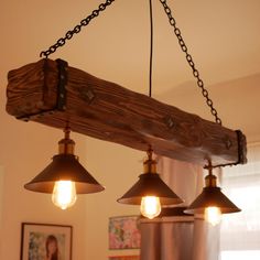 three light fixtures hanging from a wooden beam