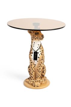 a small table with a leopard figurine sitting on it's base and a glass top