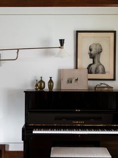 a black piano sitting in the corner of a living room with pictures on the wall