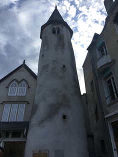 a tall white tower sitting next to two buildings under a cloudy blue cloud filled sky