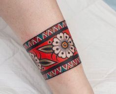 a woman's arm with a colorful bracelet on her left wrist and an orange flower in the center