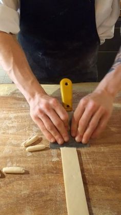 a man is using a knife to cut wood pieces on a table with other tools