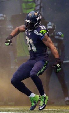 a football player running on the field with his foot in the air while wearing green and black gloves