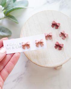 a hand holding a card with pink bows on it next to a small wooden box