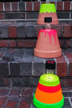 three different colored cones sitting on top of brick steps next to each other, one with a liquid pouring out of it