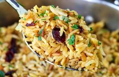 a spoon full of rice with cranberries and herbs