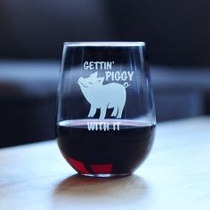 a wine glass that says gettin'piggy with it sitting on a table