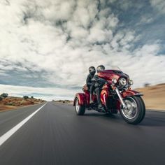 two people riding on the back of a red motorcycle