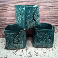 four green ceramic planters sitting on top of a doily