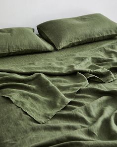 an unmade bed with green sheets and pillows