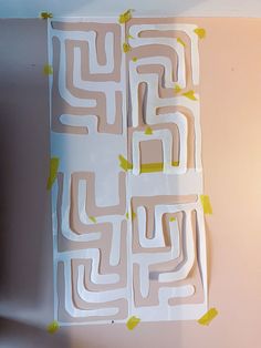 a piece of paper cut out to look like a maze with yellow tape on it