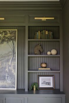 the bookshelves in this room are painted gray and have pictures on them as well