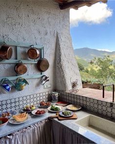 an outdoor kitchen with pots and pans hanging on the wall next to a sink