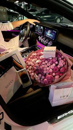 a woman sitting in the back seat of a car holding a bouquet of pink roses