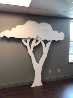 a large paper cut out of a tree with clouds on it in an office space