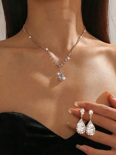 a woman wearing an elegant necklace and earring with two pear shaped diamonds on it