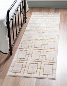 a white and gold rug on the floor next to a bed